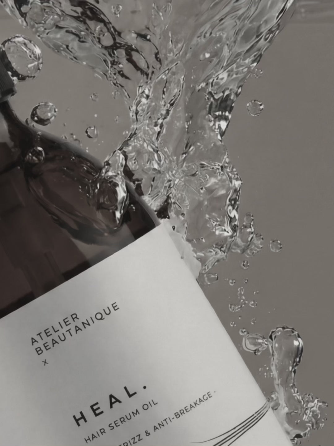 Atelier Beautanique HEAL. Anti-Frizz Hair Serum Oil Bottle on Grey Background with Light Shadow